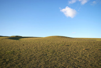 circular saucer barrow on a downland slope