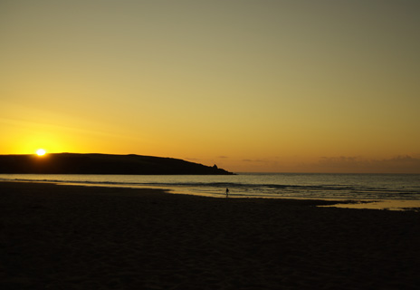 beach in Cornwall at sunset with distant female figure wading ashore